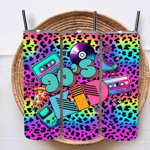 May include: Three 90s-themed tumbler cups with a leopard print background. The tumblers feature a variety of 90s icons including a cassette tape, a record, a peace sign, a pizza slice, a video game, and roller skates.