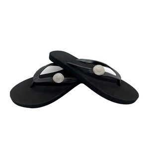 May include: Pair of black flip-flops with a jeweled embellishment on each strap.