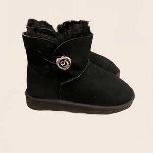 May include: Black suede ankle boots with a faux fur lining and a decorative rose-shaped button.