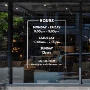 May include: A white sign with black text on a glass storefront window displays business hours. The sign reads "HOURS", "MONDAY - FRIDAY 9:00am - 5:00pm", "SATURDAY 10:00am - 2:00pm", "SUNDAY Closed", "123-456-7890", and "www.yourwebsitehere.com".