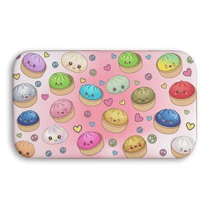 May include: A rectangular, rounded-corner item featuring a repeating pattern of cartoon dumplings in various colors, including purple, green, blue, and yellow, with smiling faces. Pink hearts and peace signs are scattered across a light pink background.