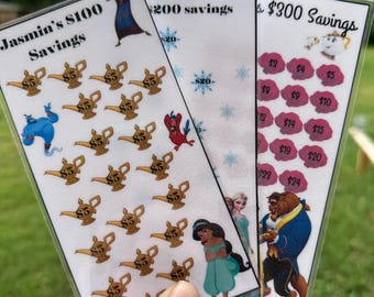 Op de afbeelding: Drie kleurrijke kaarten met Disney-figuren en spaardoelen. De eerste kaart toont Jasmine uit Aladdin en heeft een doel van € 100. De tweede kaart toont Elsa en Anna uit Frozen en heeft een doel van € 200. De derde kaart toont Belle en het Beest uit Belle en het Beest en heeft een doel van € 300.