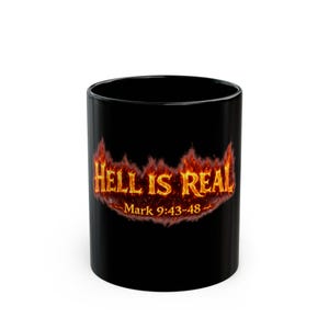 May include: Black ceramic mug with the text "HELL IS REAL" in fiery orange and yellow lettering. Below the text is "Mark 9:43-48". The mug is cylindrical and has a glossy finish.
