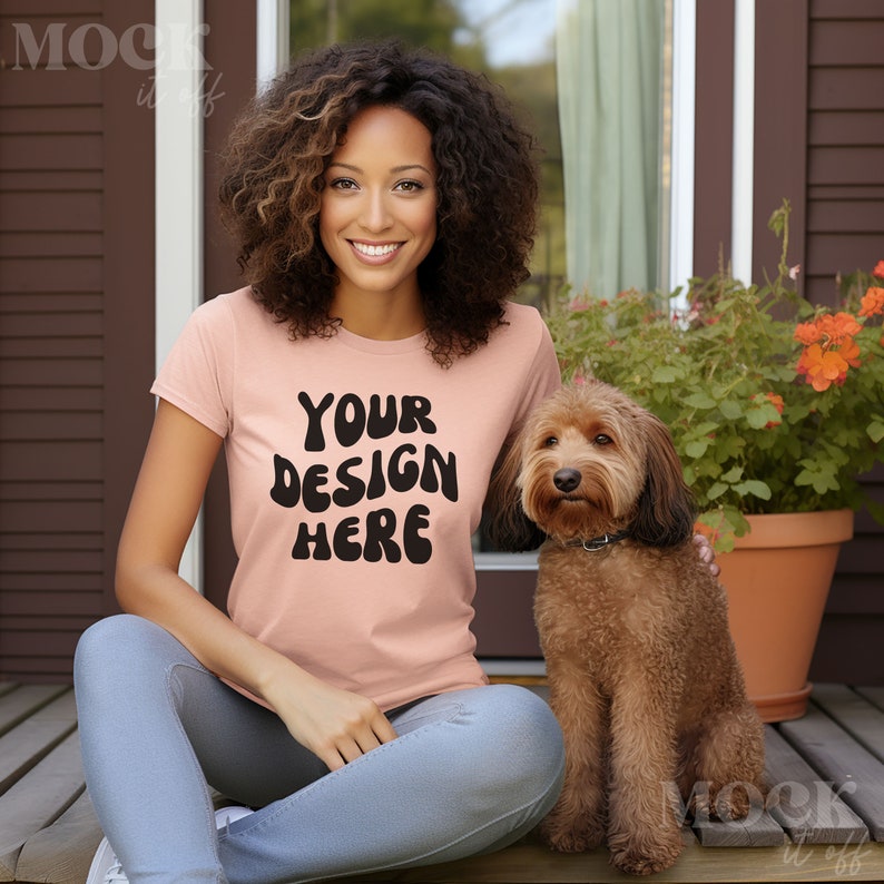 May include: A woman wearing a peach colored t-shirt with the text "YOUR DESIGN HERE" in black. She is sitting on a wooden deck with a brown dog sitting next to her.