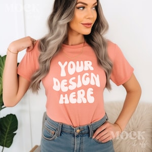 May include: A coral pink t-shirt with short sleeves and a white graphic that says "YOUR DESIGN HERE" in a retro font.