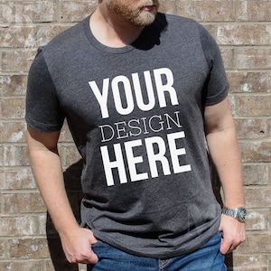 May include: A dark grey t-shirt with the text "YOUR DESIGN HERE" printed in white on the front.