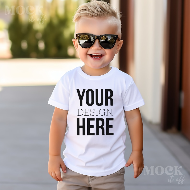 May include: A young boy wearing sunglasses and a white t-shirt with the text "YOUR DESIGN HERE" printed on it.