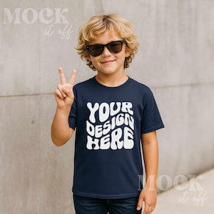 May include: A navy blue t-shirt with the text "YOUR DESIGN HERE" in white, worn by a child wearing sunglasses and making a peace sign.
