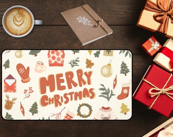 以下が含まれることがあります： 茶色の文字で「MERRY CHRISTMAS」と書かれた、お祝いのクリスマスのデザインの長方形のベージュのマウスパッド。セーター、オーナメント、ミトンなどのイラストが描かれています。コーヒーカップと包装されたギフトも表示されています。