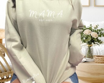 Puede incluir: Una sudadera de color verde claro con el texto "MAMA EST 2023" en la parte delantera y el texto "Remington" con un corazón en la manga izquierda.