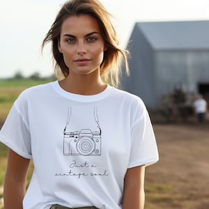 May include: White t-shirt with a black line drawing of a camera with a strap and the text "Just a vintage soul".