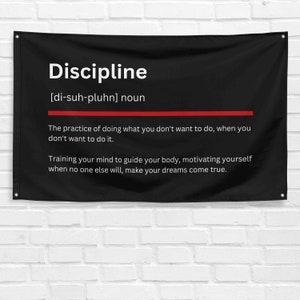 Puede incluir: Bandera de pared negra con la palabra "Discipline" en blanco, junto con su pronunciación y definición. Una línea roja separa el título de la definición. La definición está en texto blanco.