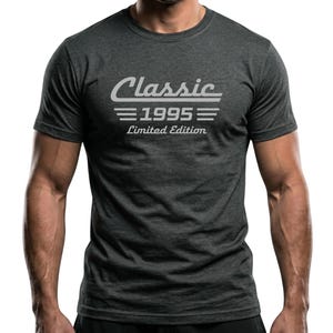 Può includere: T-shirt grigio scuro con la scritta bianca "Classic 1995 Limited Edition". La maglietta ha un girocollo e maniche corte. Il testo è in un font stilizzato.