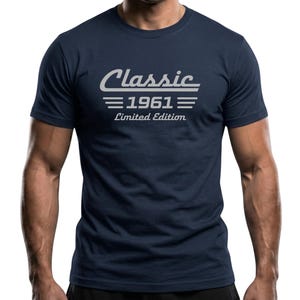 Könnte beinhalten: Marineblaues T-Shirt mit dem Text "Classic 1961 Limited Edition" in weißer, stilisierter Schrift. Das Design enthält das Wort "Classic" über dem Jahr 1961, mit horizontalen Linien, die den Text trennen. Das T-Shirt hat kurze Ärmel.