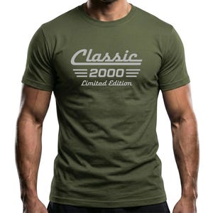 May include: Olive green t-shirt with the text "Classic 2000 Limited Edition" in a white, retro-style font. The shirt has a crew neck and short sleeves. The image is a medium shot.