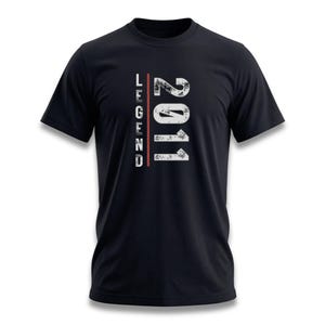 May include: Black t-shirt with the word "LEGEND" in white vertically on the left side and the number "2011" in white on the right side. A red vertical line separates the two words. The design has a distressed, vintage look.