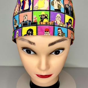 May include: A colorful surgical scrub cap featuring a grid pattern of professional wrestling figures. The cap is made of fabric and has a variety of colors including yellow, pink, purple, and blue. The cap is displayed on a mannequin head.