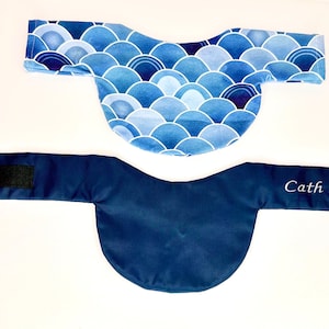 May include: Two eye masks. One is navy blue with a velcro closure. The other is blue with a white wave pattern. The text "Cath Lab" is embroidered on the navy blue mask.