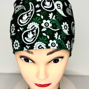 Peut inclure: Un bonnet de chirurgien vert foncé avec un motif cachemire et floral blanc. Le bonnet présente des fleurs blanches, des feuilles et des motifs cachemire avec un contour blanc. Le bonnet est sur une tête de mannequin.