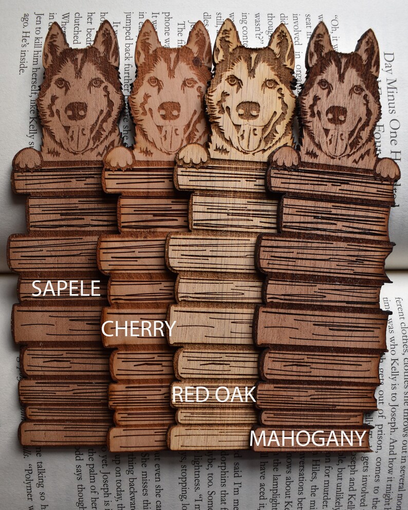 May include: Four wooden bookmarks with a laser-engraved image of a husky dog peeking over a stack of books. The bookmarks are made of different types of wood: Sapele, Cherry, Red Oak, and Mahogany.