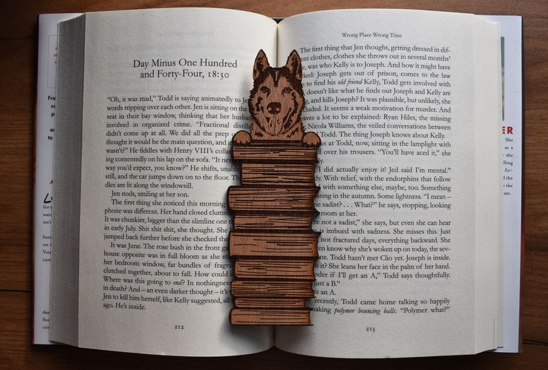 May include: A wooden bookend featuring a cartoon husky dog peeking over a stack of books. The bookend is painted in shades of brown and has a detailed design.