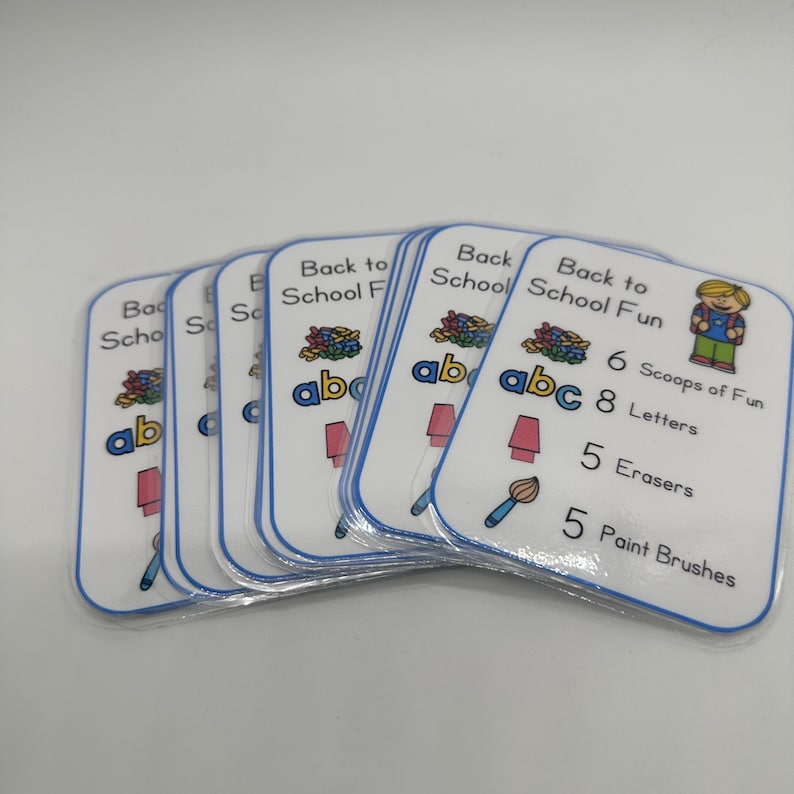 May include: A set of colorful cards with the text "Back to School Fun" and a cartoon image of a child with a backpack. The cards list school supplies with numbers, such as 6 scoops of fun, 8 letters, 5 erasers, and 5 paint brushes.