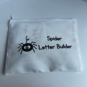 May include: White canvas zippered pouch with a black spider and the text "Spider Letter Builder" printed on it.