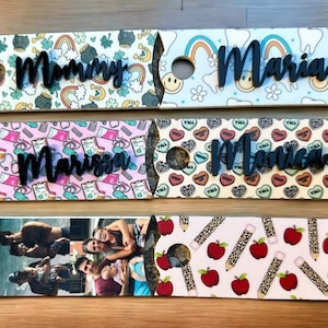 May include: Four personalized wine bottle gift bags with different patterns. The bags are made of cardboard and have a cut-out hole for the bottle neck. The names "Mommy", "Maria", "Marissa", and "Monica" are written on the bags.