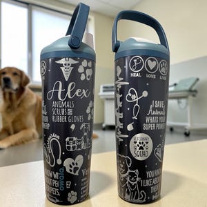 Könnte beinhalten: Zwei dunkelblaue Owala-Wasserflaschen mit weißen grafischen Designs zum Thema Veterinärmedizin, darunter Pfotenabdrücke, Stethoskope und der Text "Alex", "I save animals, what's your super power?", "Heal Love Live" und "Veterinary Squad."