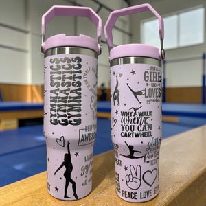 May include: Two light purple stainless steel tumblers with handles, featuring black graphic prints of gymnasts, hearts, stars, and text including "Gymnastics," "Just a girl who loves gymnastics," "Why walk when you can cartwheel," and "Peace love gym."