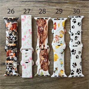 May include: Five different Apple Watch bands with various colorful patterns. The bands are numbered 26 through 30. The patterns include cats, flamingos, a Highland cow, bees and honeycombs, and paw prints.