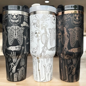 May include: Three stainless steel tumblers with a skeleton and radiation symbol design. The tumblers are black, white, and copper.