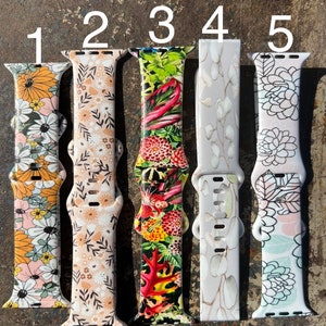 May include: Five different Apple Watch bands with floral patterns. The bands are numbered 1 through 5. The bands are all white with different floral patterns.