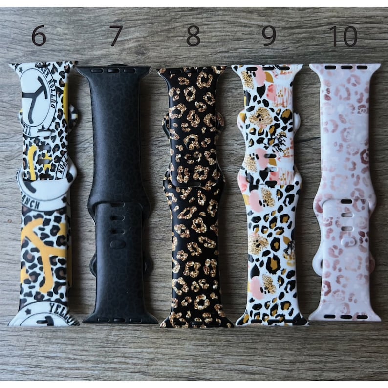 May include: Five different Apple Watch bands with leopard print designs. The bands are in black, gold, white, and pink.