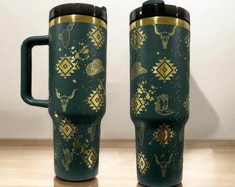 Peut inclure: Deux tasses de voyage vertes et dorées avec un motif sud-ouest. Les tasses présentent un motif géométrique, un cactus et un crâne. Une tasse a une poignée.
