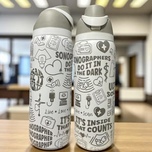 Peut inclure: Deux gourdes blanches avec des couvercles gris arborant un motif répétitif d'icônes d'échographie médicale et de textes tels que "Sonographers do it in the dark", "Scan til it hertz" et "It's inside that counts" en encre gris foncé.