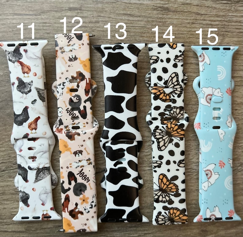 May include: Five different Apple Watch bands with various patterns. The bands are numbered 11 through 15. The patterns include chickens, dogs, cow print, butterflies, and llamas.