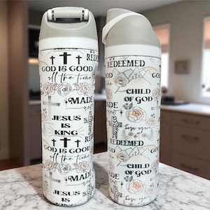 Puede incluir: Dos botellas de agua blancas con tapas grises. Las botellas están decoradas con diseños florales y de cruces, y texto inspirador que incluye "Dios es bueno" y "Jesús es el Rey".