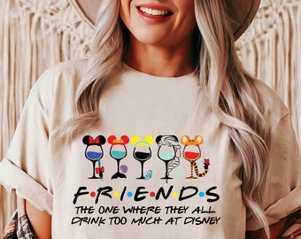 Op de afbeelding: Een wit T-shirt met een afbeelding van wijnglazen met Disney-personage oren. De tekst "FRIENDS THE ONE WHERE THEY ALL DRINK TOO MUCH AT DISNEY" is onder de glazen gedrukt.