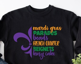 May include: Black sweatshirt with a purple fleur-de-lis and the text "Mardi Gras", "Parades", "beads", "French Quarter", "Beignets", and "King cake" in green, orange, and purple.