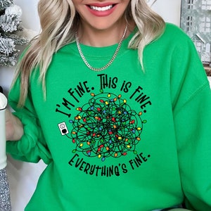 May include: Green Christmas sweatshirt with the text "I'm fine. This is fine. Everything's fine." and a tangled string of Christmas lights.