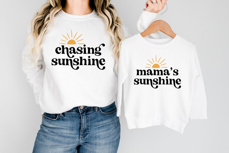 May include: White long-sleeved shirts with a sun graphic and text. One shirt says "chasing sunshine" and the other says "mama's sunshine".
