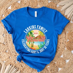 May include: Royal blue t-shirt featuring a circular design with the text "Larkins Family Hawaii Celebrating Gary & Judy 50 Years 2025". The design includes palm trees, a beach scene, and tropical foliage.