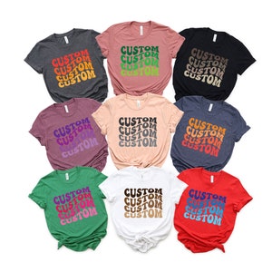 May include: Ten t-shirts in various colors with the word "CUSTOM" repeated in a retro font style. The shirts are arranged in a circle with the text facing outward.