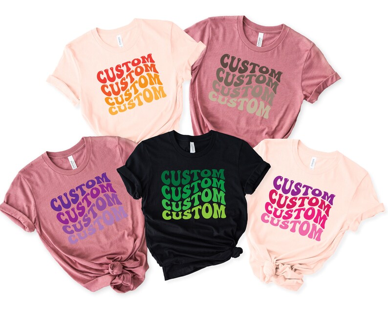 May include: Five t-shirts with the word "CUSTOM" repeated in a retro font in different colors. The shirts are in various colors, including pink, black, and brown.
