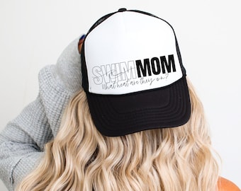 May include: Black and white trucker hat with the text "Swim Mom What heat are they on?" on the front. The hat is worn by a person with long blonde hair.