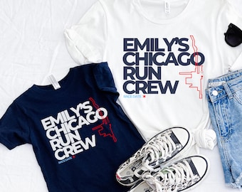 May include: Two t-shirts, one navy blue and one white, with the text "EMILY'S CHICAGO RUN CREW". The design includes a red graphic and the words "RACE DATE". A pair of leopard print trainers and denim shorts are also in the image. The text is in white and navy blue.