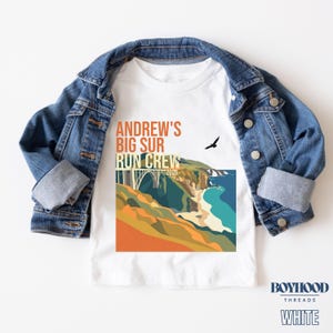 May include: White t-shirt with a Big Sur graphic and the text "Andrew's Big Sur Run Crew 2026". The shirt is displayed on a blue denim jacket.