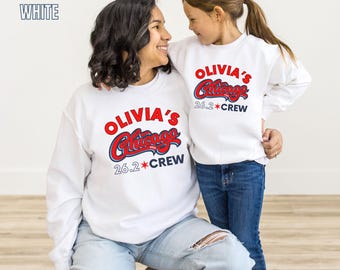 May include: Two white sweatshirts with the text "OLIVIA'S Chicago 26.2 CREW" in red and blue. The sweatshirts are worn by a woman and a child, both smiling. The image includes the text "BOYHOOD THREADS" and "WHITE".