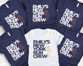 May include: Five navy blue t-shirts with white text that reads "Emily's New York Run Crew" and a small orange illustration of the Statue of Liberty. One white t-shirt with the same text and illustration.